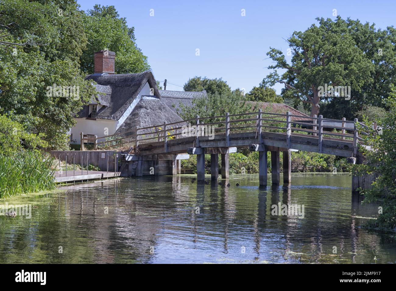wooden arched bridge and thatched cottage in flatford, suffolk Stock Photo