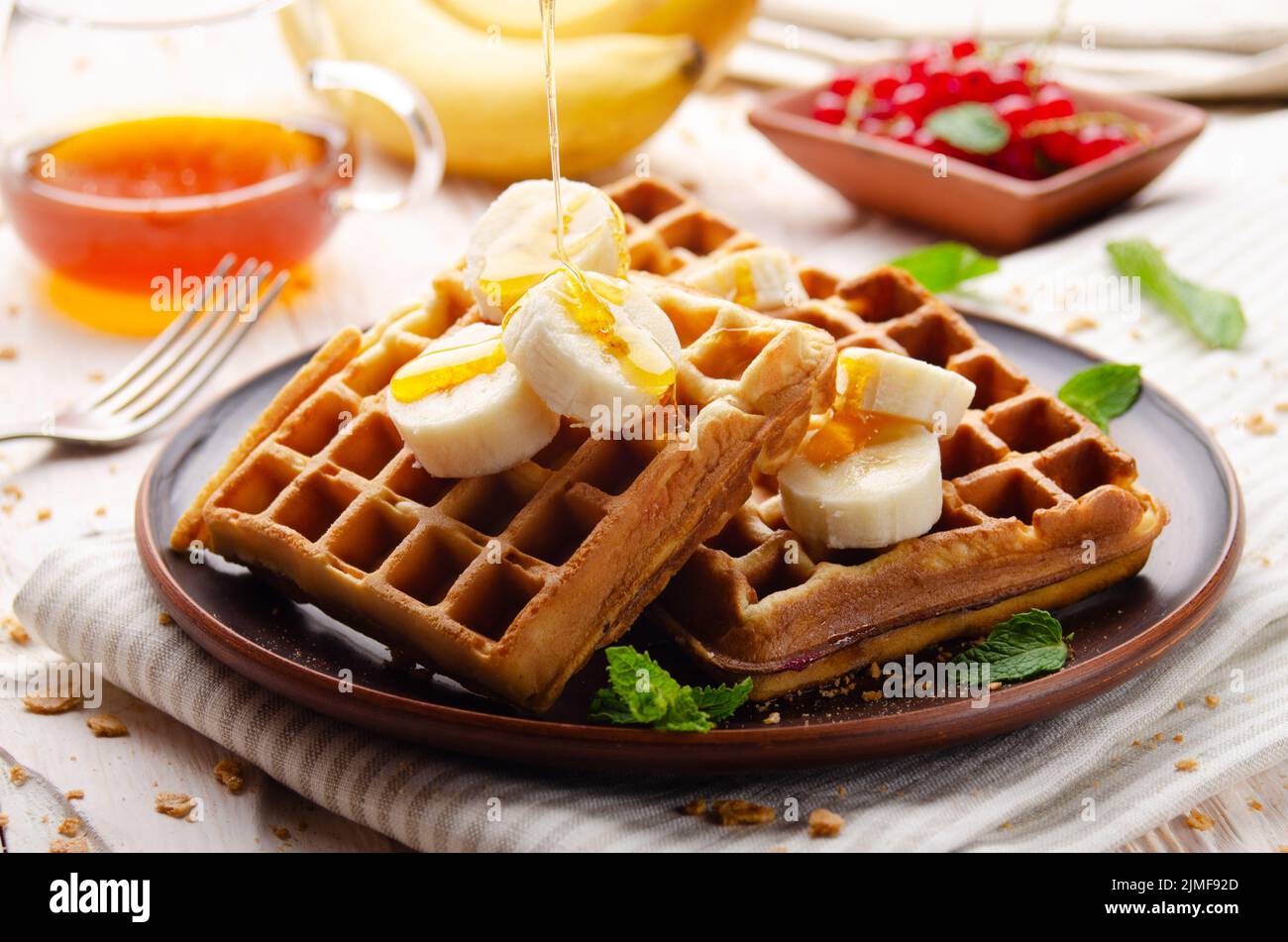 Homemade crispy Belgian waffles served with banana and honey Stock Photo