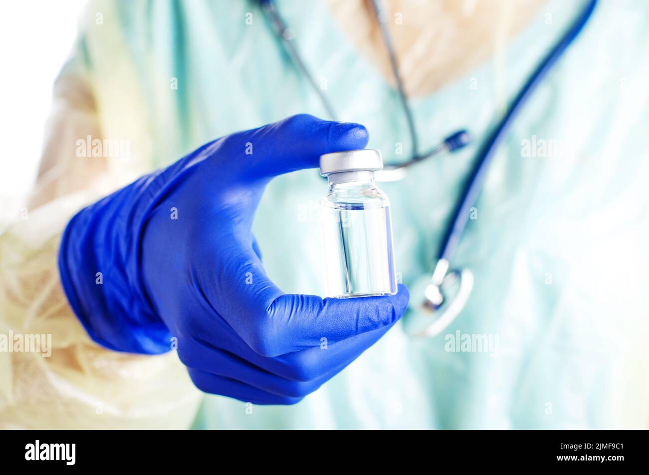 A nurse in safety gloves holds bottle with liquid medicine for injections Stock Photo