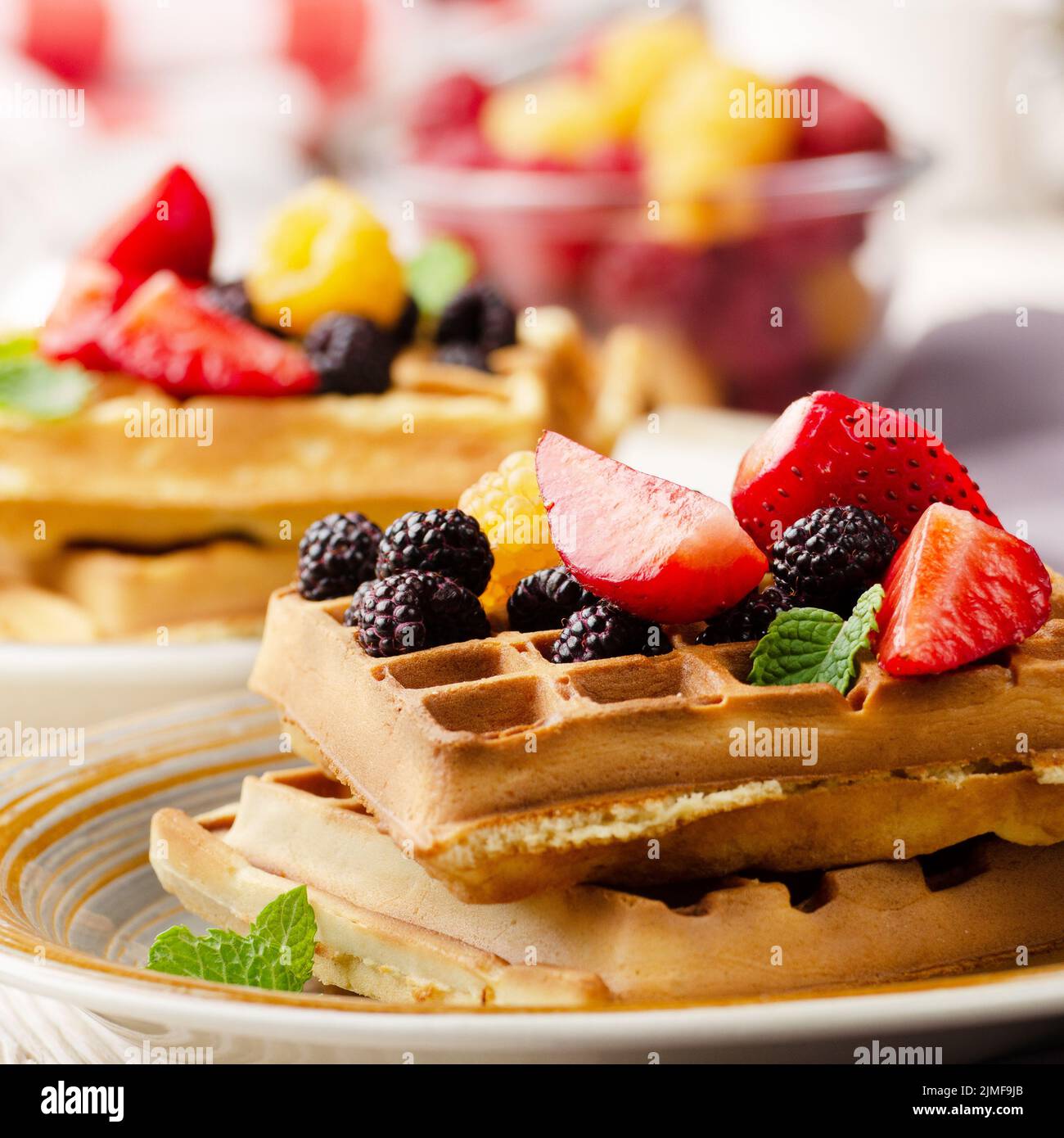 CLoseup view at belgian waffles served with strawberries and blackberries on kitchen table Stock Photo