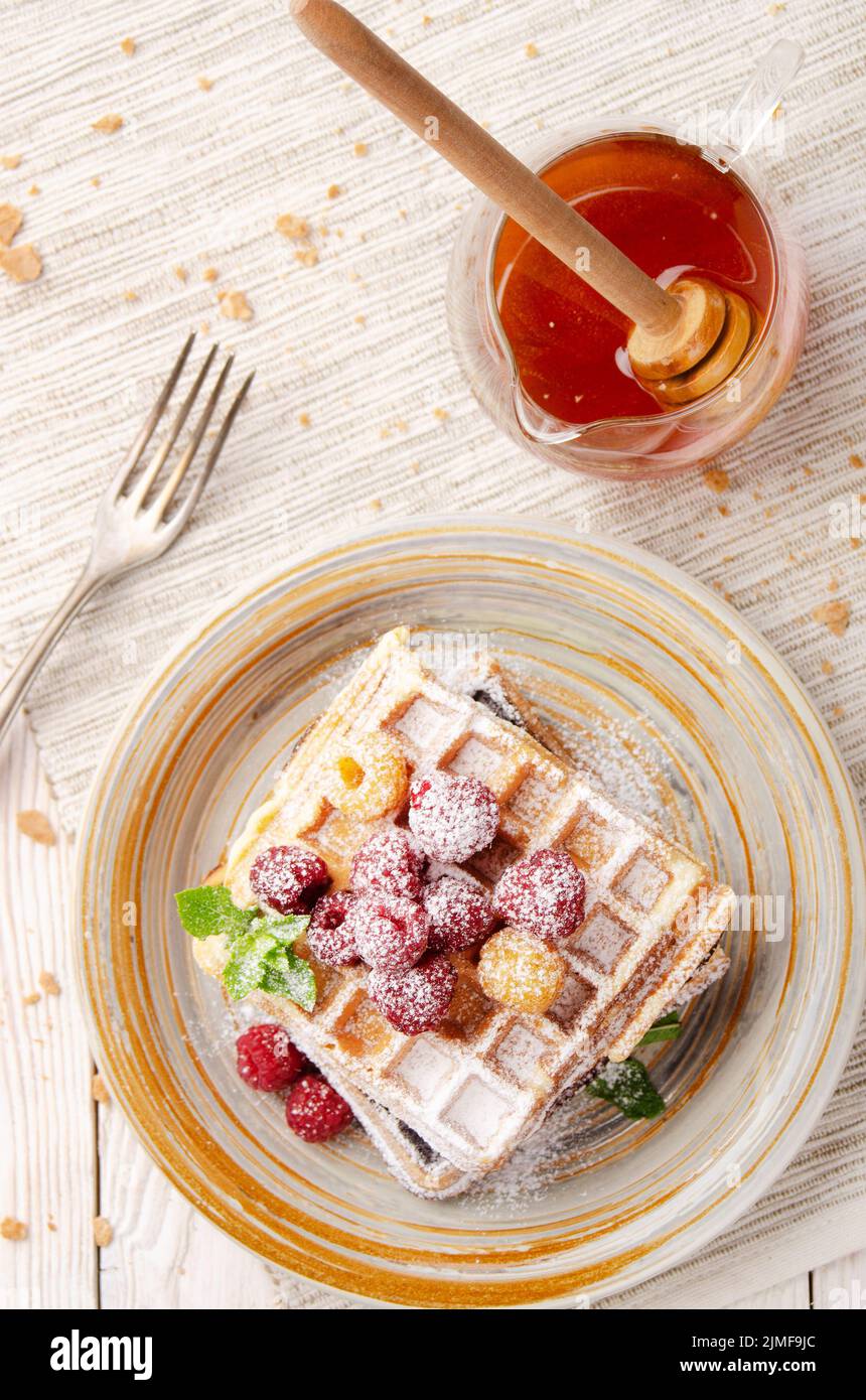 Flat lay view at Belgian waffles served with raspberries and mint leaf dusted with powdered sugar Stock Photo