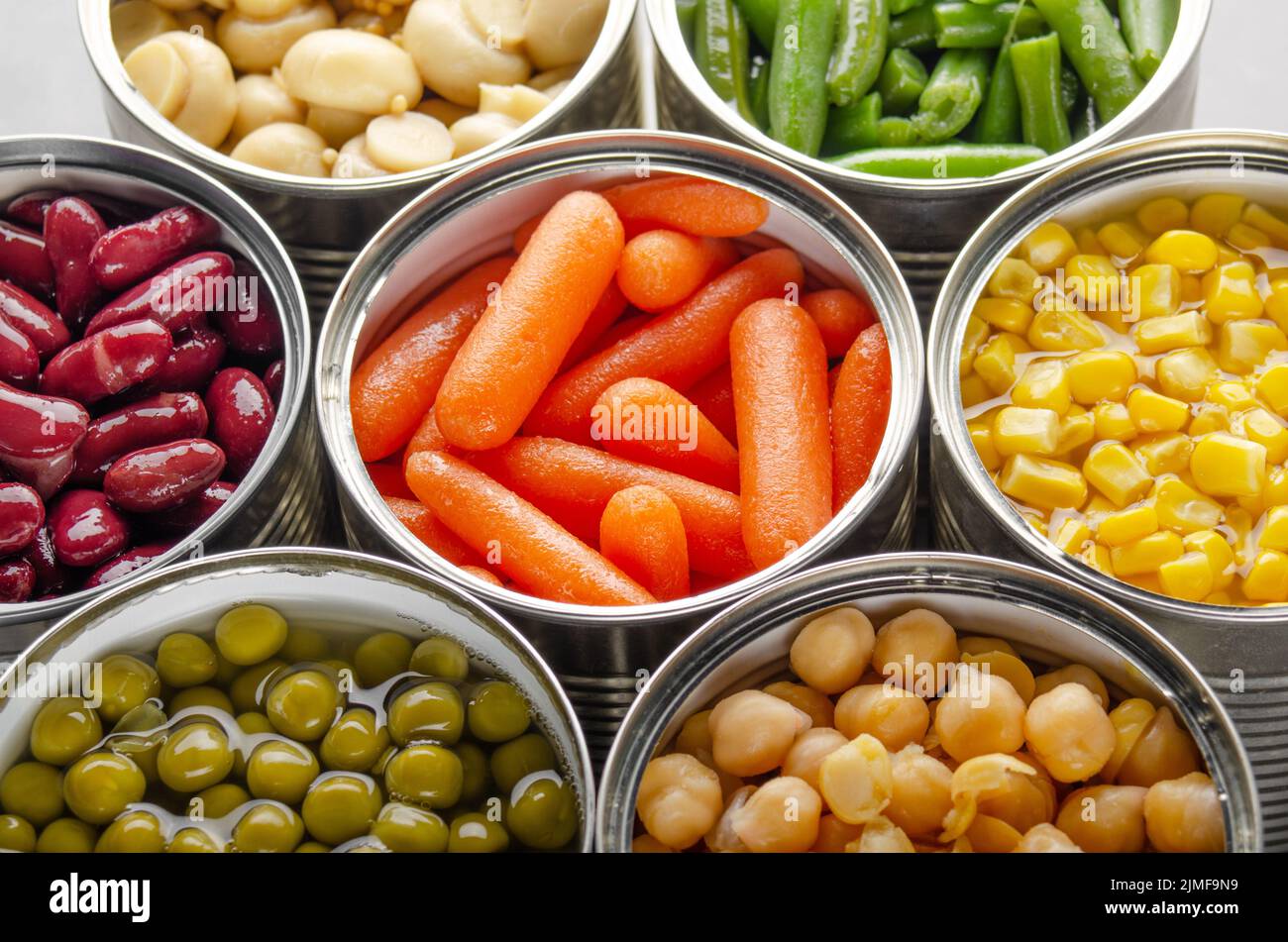 Canned vegetables in opened tin cans on kitchen table. Nonperishable long shelf life foods