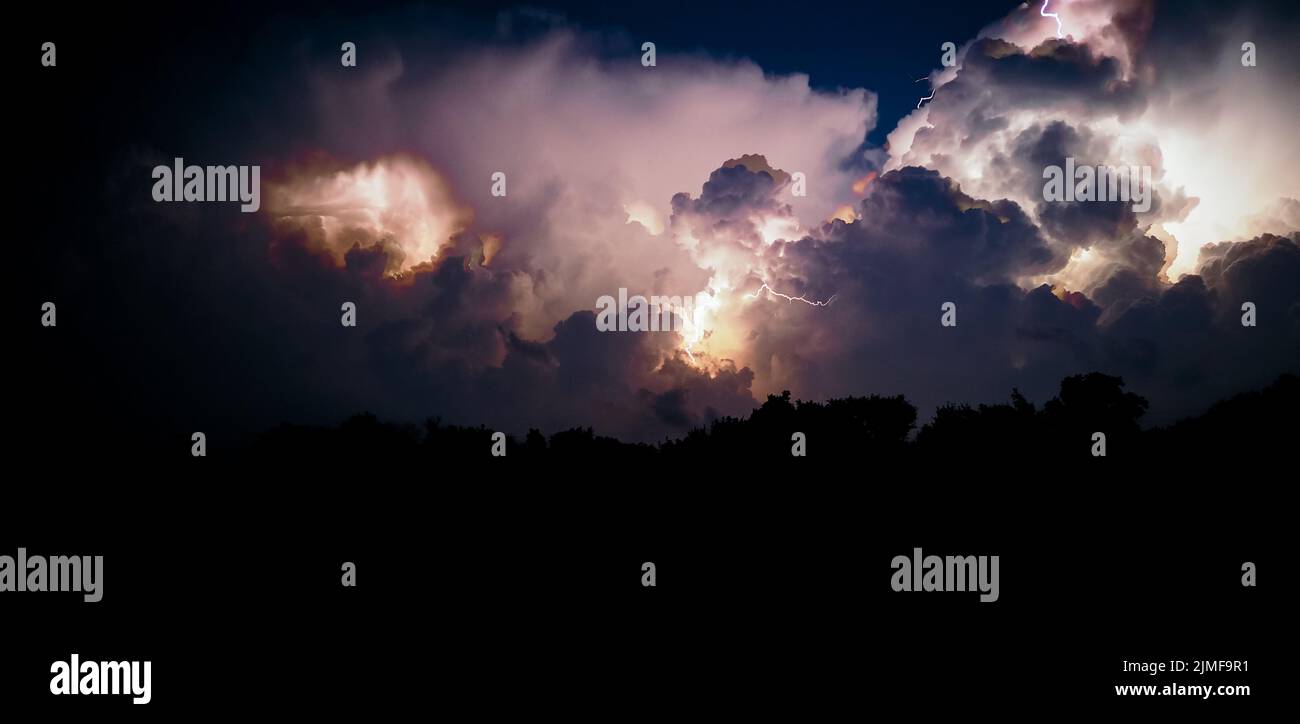 Thunderclouds and lightning flashes during a thunderstorm at night. Stock Photo