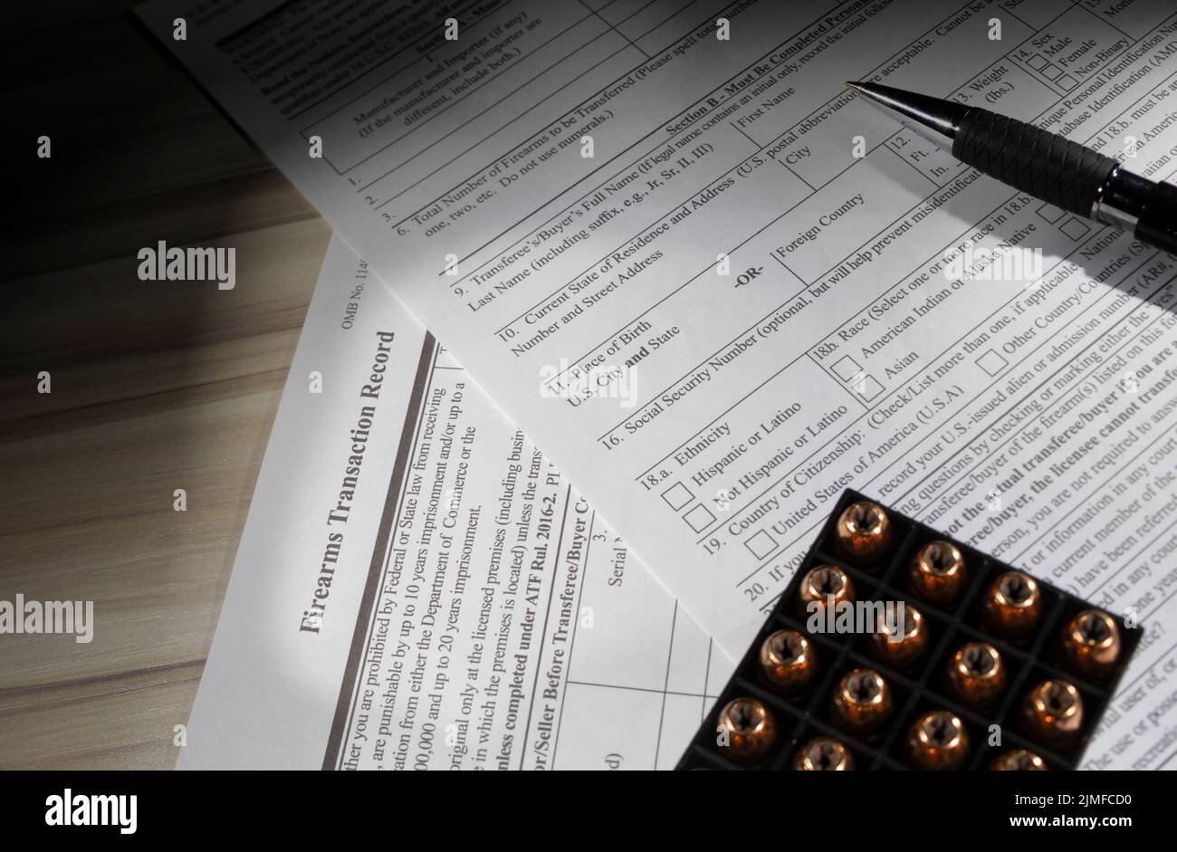 Box of ammunition with pen resting on the public domain forms that are used by the FBI for NICS background checks. Stock Photo