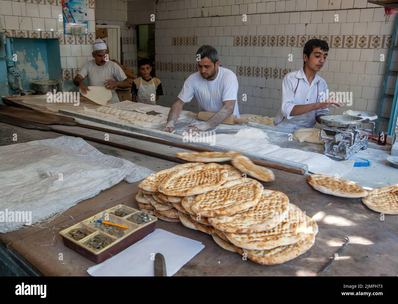 Men and boys busy at work making Turkish flat bread in a bakery in Sanliurfa in eastern Turkey. Bread is the staple of the Turkish diet. Stock Photo