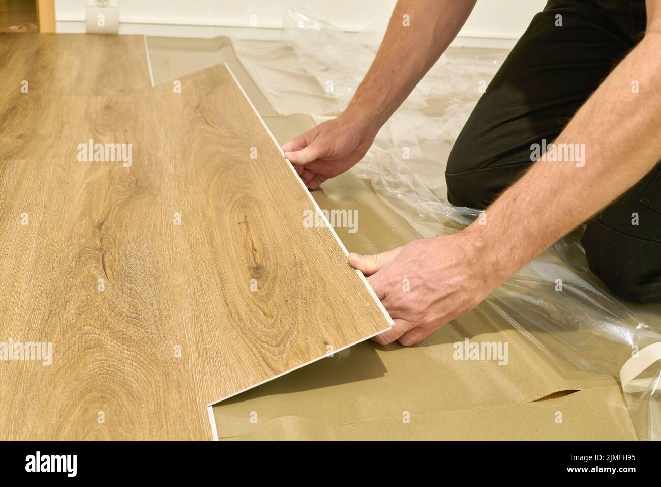 Craftsman renovating an apartment and laying a click vinyl floor covering Stock Photo