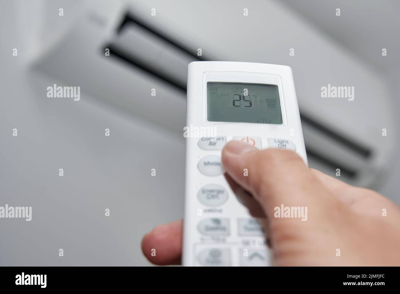 Hand of a man pressing the buttons on the control of a split air