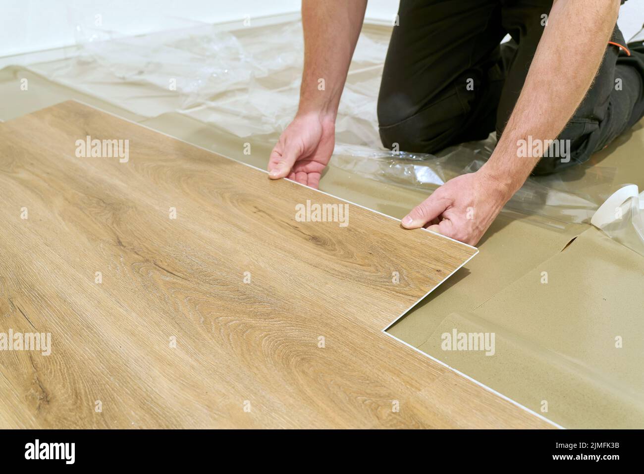 Craftsman renovating an apartment and laying a click vinyl floor covering Stock Photo