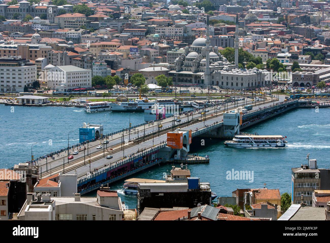 A view looking towards Galata Bridge on Golden Horn at Istanbul in Turkey as a ferry boat passes under. Stock Photo