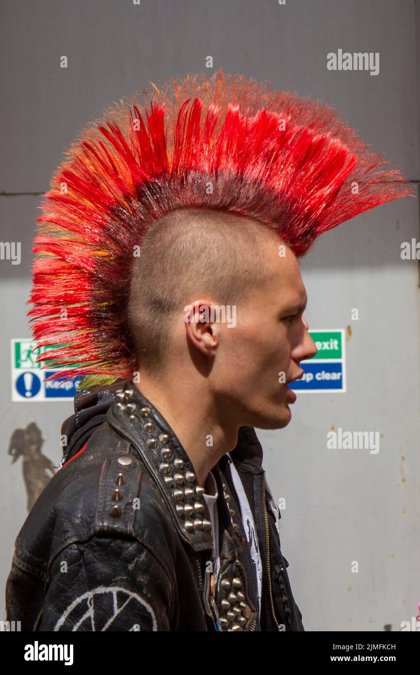 Shaved head with red Liberty Spikes inBlackpool, Lancashire, UK. 6th Aug 2022. The punk subculture, ideologies, and fashion, with Mohican dyed hairstyles and colouring at the Punk Rebellion festival at The Winter Gardens. A protest against conventional attitudes and behaviour, a clash of anti-establishment cultures,  mohawks, safety pins and a load of attitude at the seaside town as punks attending the annual Rebellion rock music festival at the Winter Gardens come shoulder to shoulder with traditional holidaymakers. Stock Photo