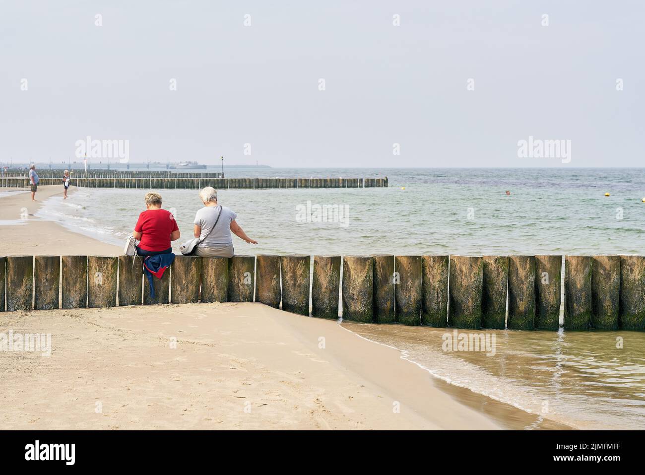 Two old vacationers on a breakwater at the beach of Kolobrzeg at the Baltic Sea in Poland Stock Photo