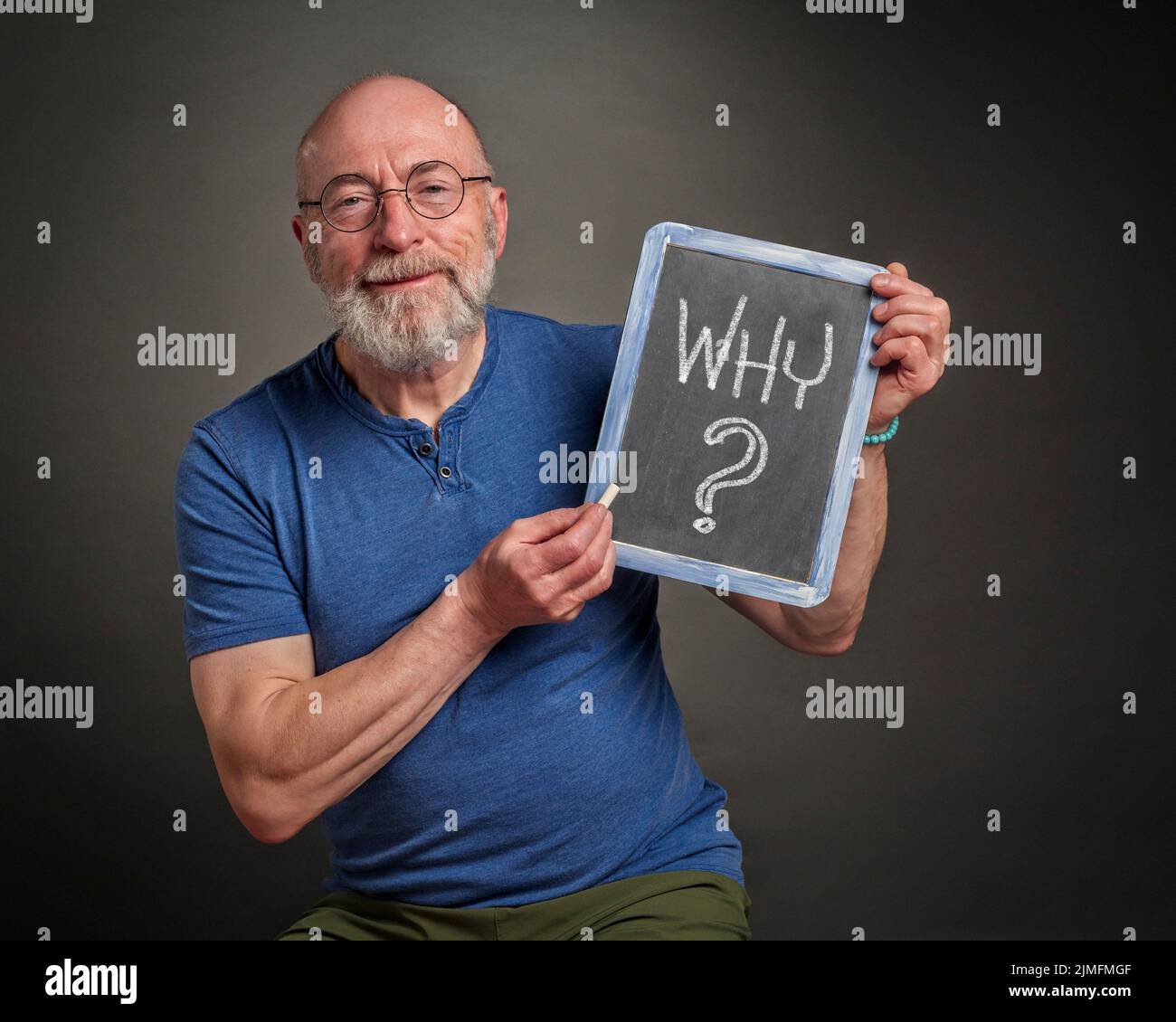 why question on a slate blackboard held by a senior man, teacher or mentor Stock Photo