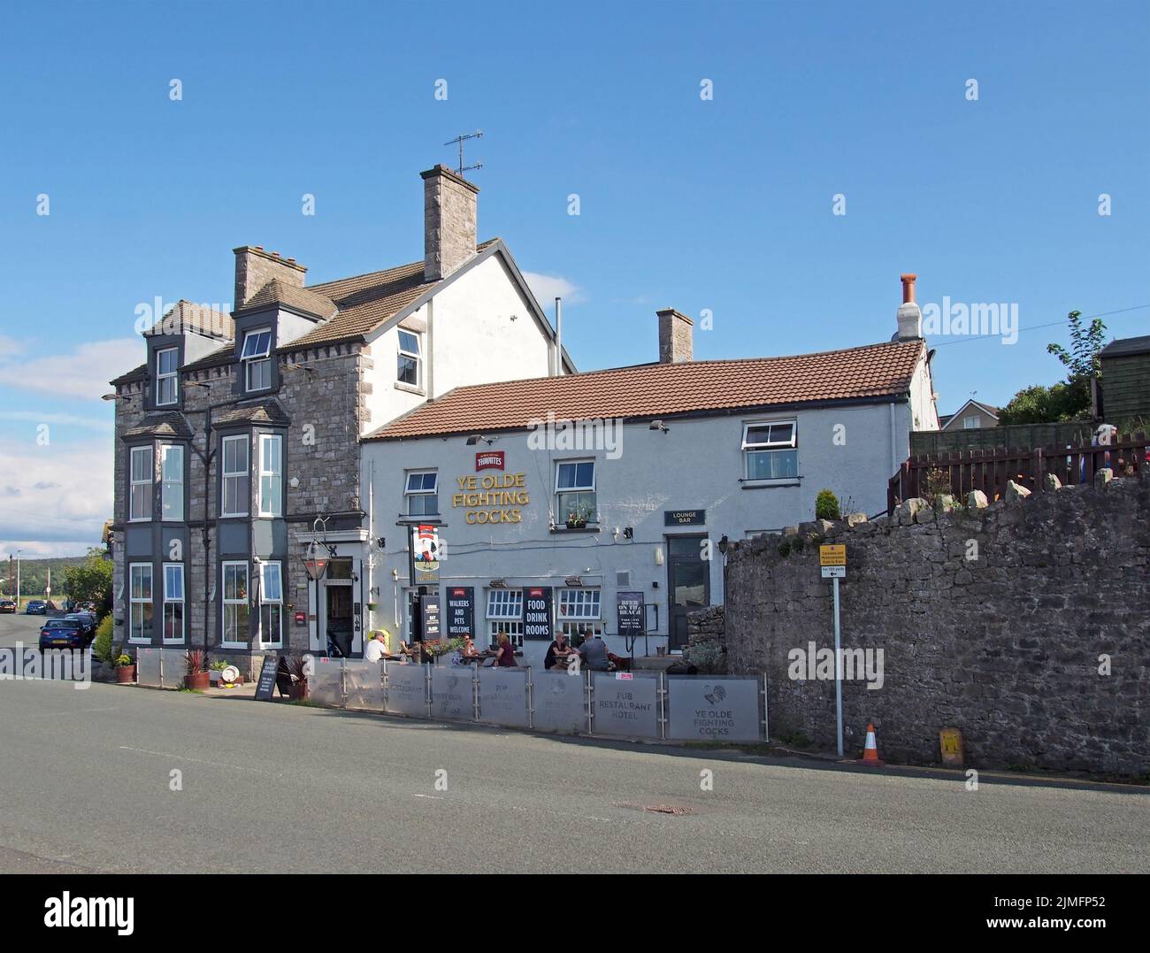 View of the ye olde fighting cocks pub in arnside in cumbria with people drinking outside in summer Stock Photo