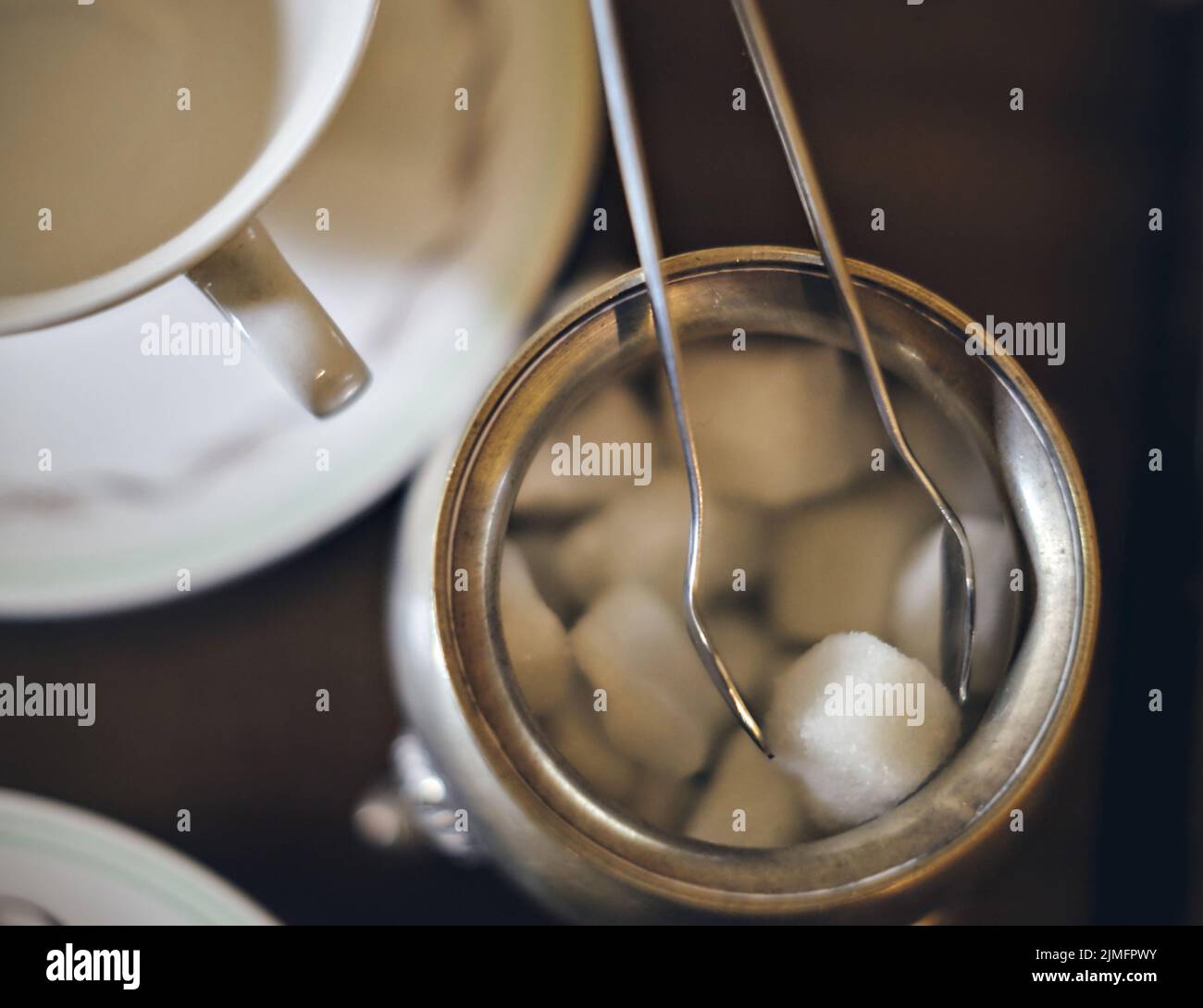 Vintage sugar tongs with sugar lump. Soft focus background. Close up