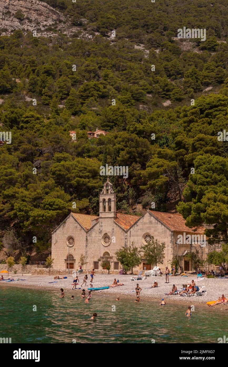 KOMIZA, VIS, CROATIA, EUROPE - People enjoy beach in coastal town of Komiza, on the island of Vis, in the Adriatic Sea. Stock Photo