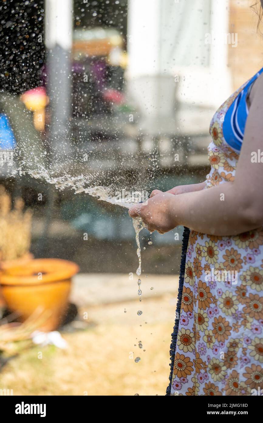 Young Woman waters garden with a hosepipe before the hosepipe ban comes