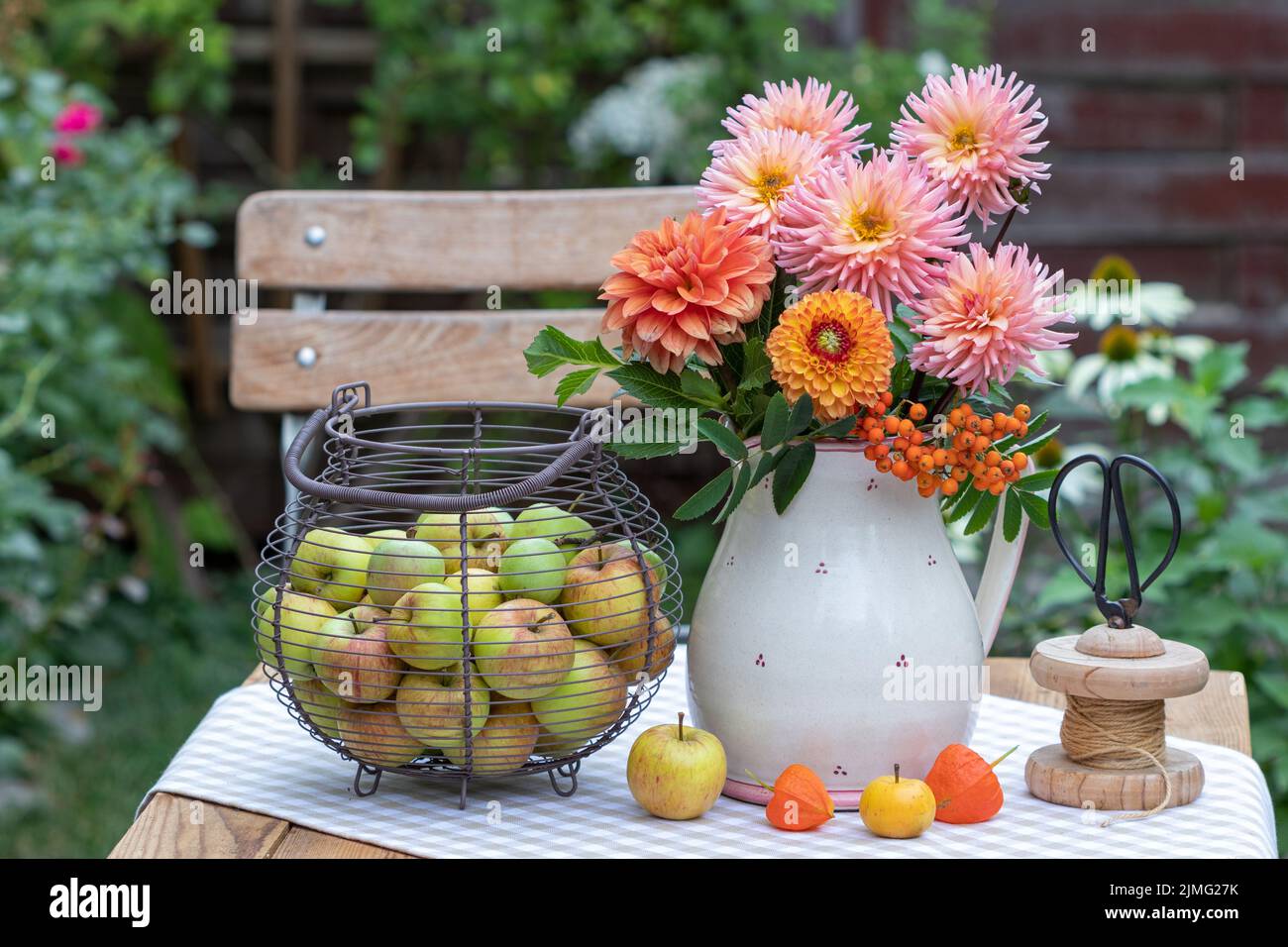 arrangement with bouquet of orange dahlias and apples in basket Stock Photo