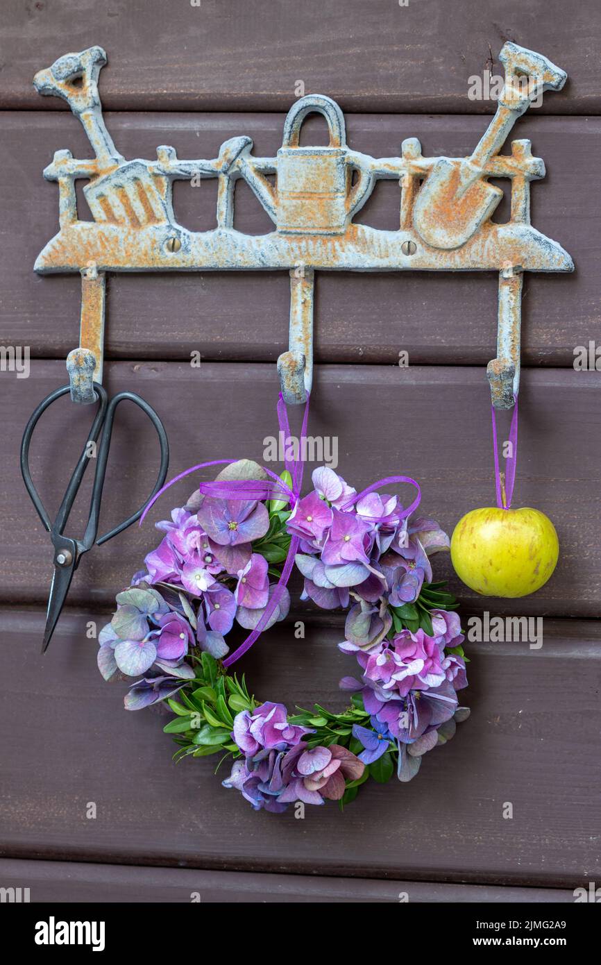 wreath of purple hydrangea flowers hanging on garden hook rail Stock Photo