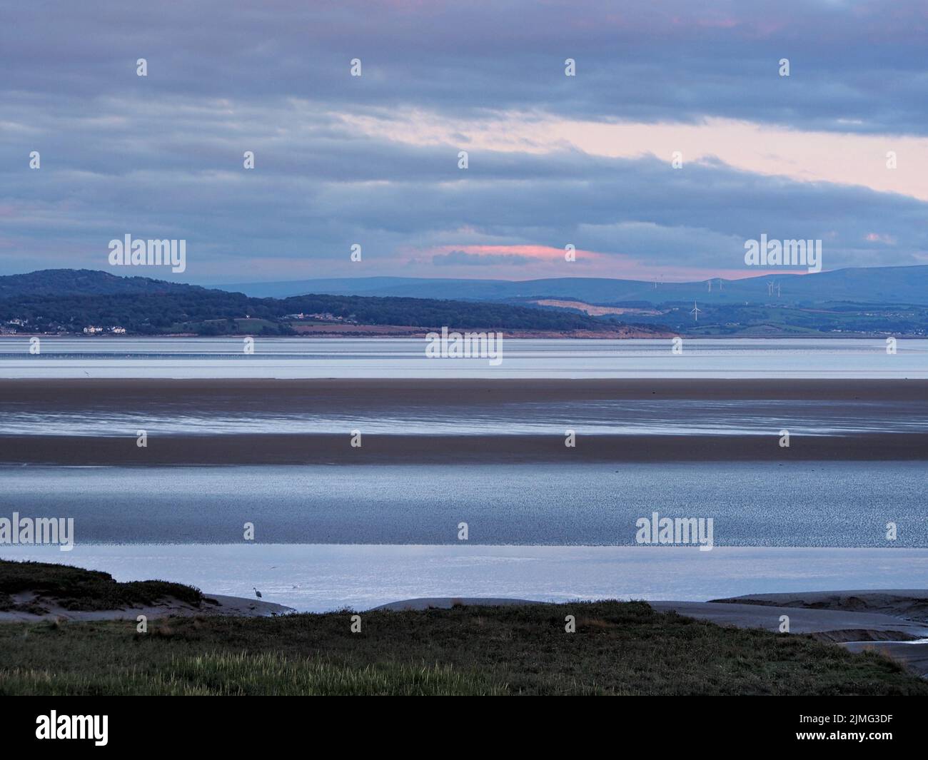 View of the coast at grange over sands in cumbria at twilight with grass covered wetland in the foregrounds and the lake distric Stock Photo