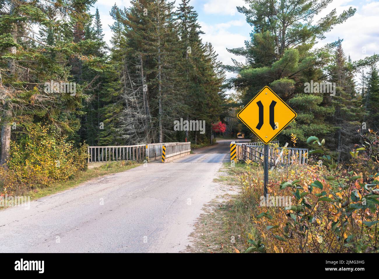One lane bridge sign along a remote forest road on a sunny autumn day. Stock Photo