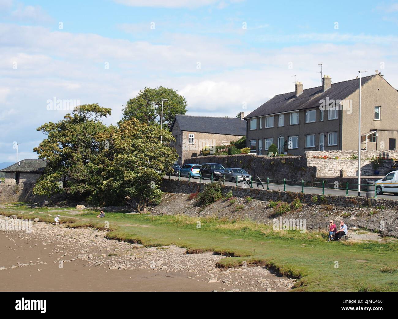 View of the houses along the coast road in arnside in cumbria with people on the beach in summer Stock Photo