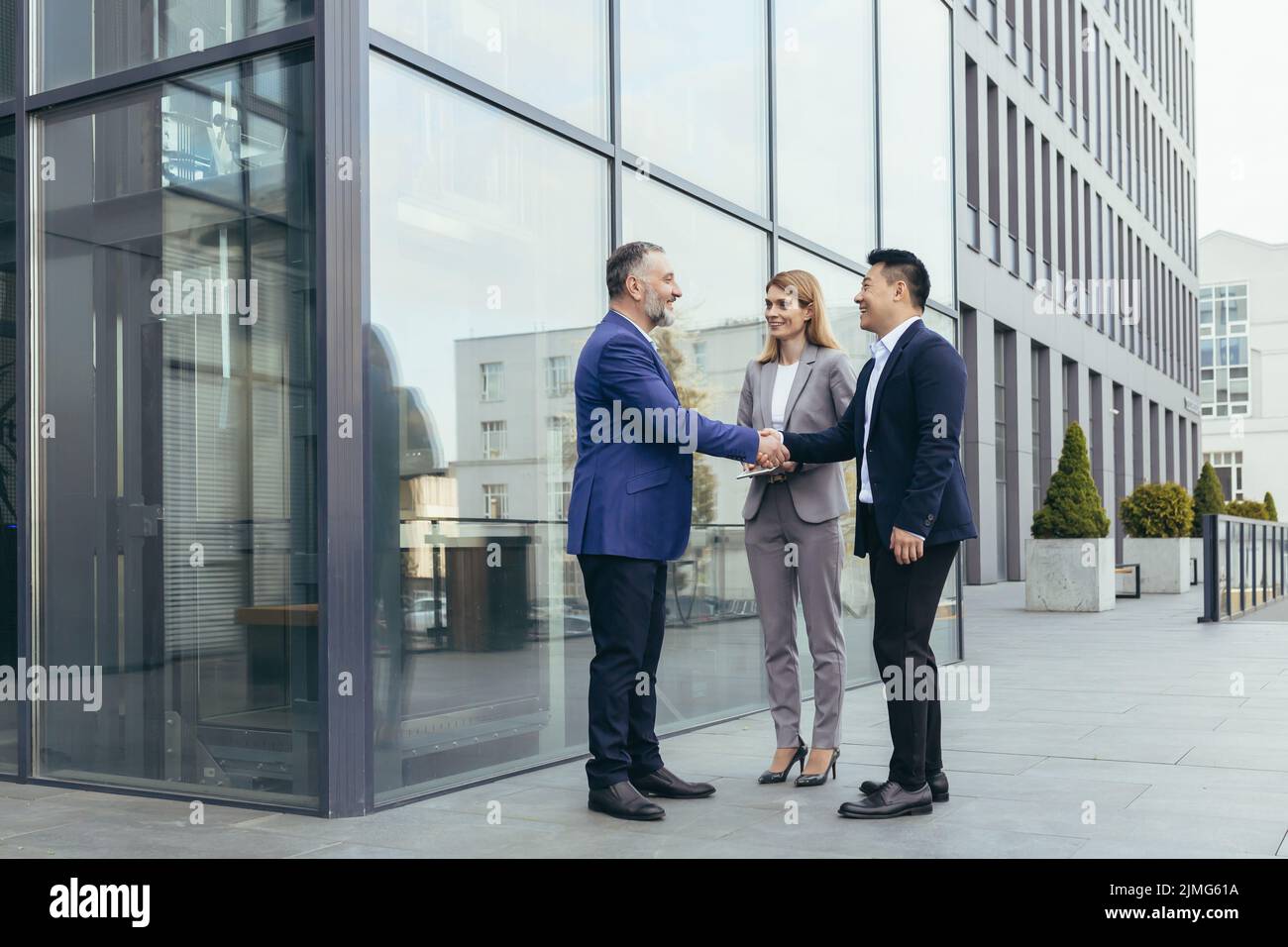 Business meet, colleagues happy team meet outside office, greet shake hands, diverse employees in business suit, man and woman business people Stock Photo