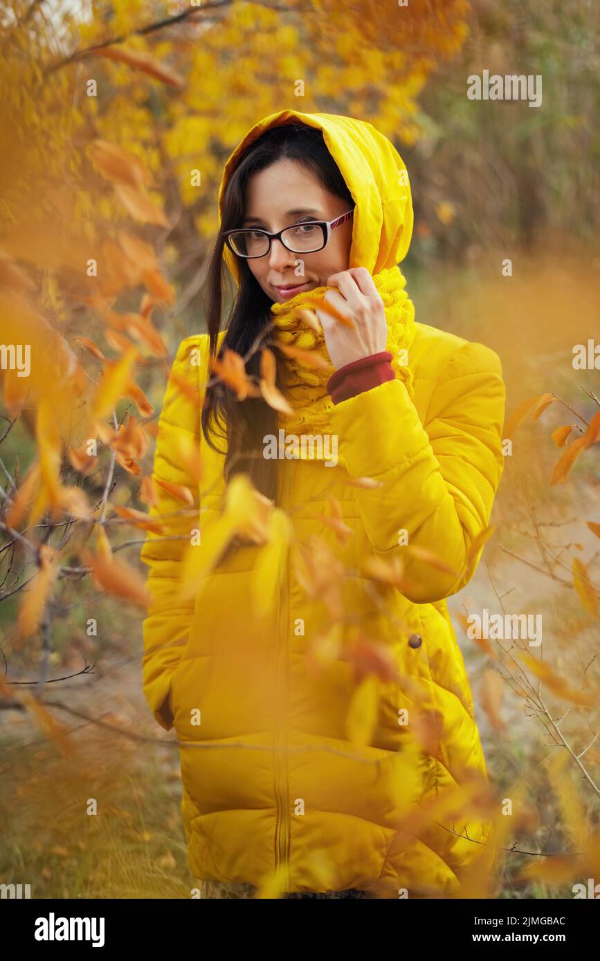 Beautiful woman in a yellow jacket and scarf on an autumn forest