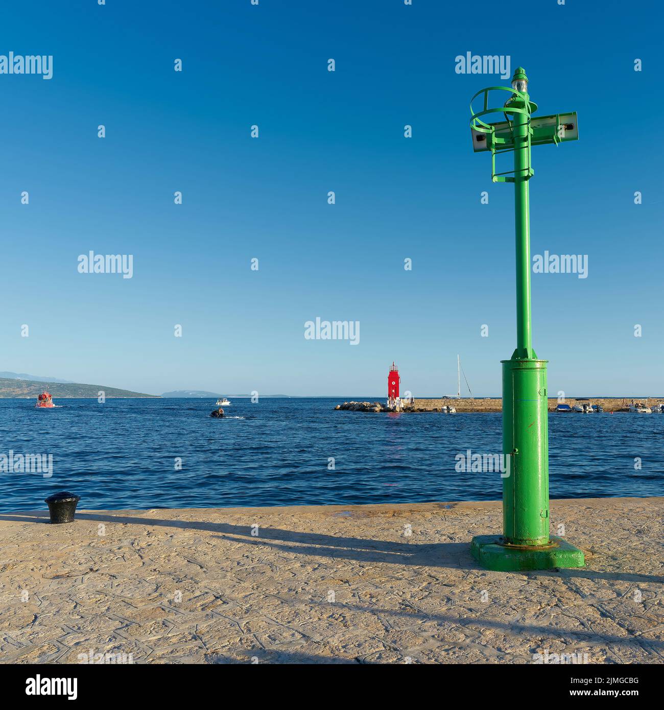 Green Lighthouse at a pier in the port of Krk on the Adriatic Sea in Croatia Stock Photo