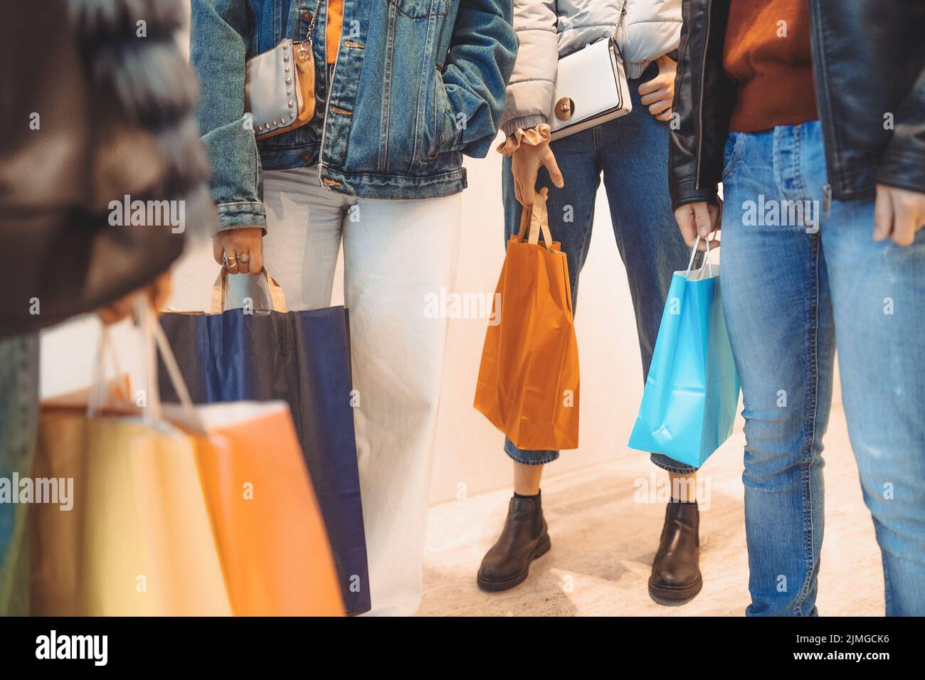 Detail of young people holding shopping bags standing in front of a window shop at the market mall center - crop shot - Stock Photo