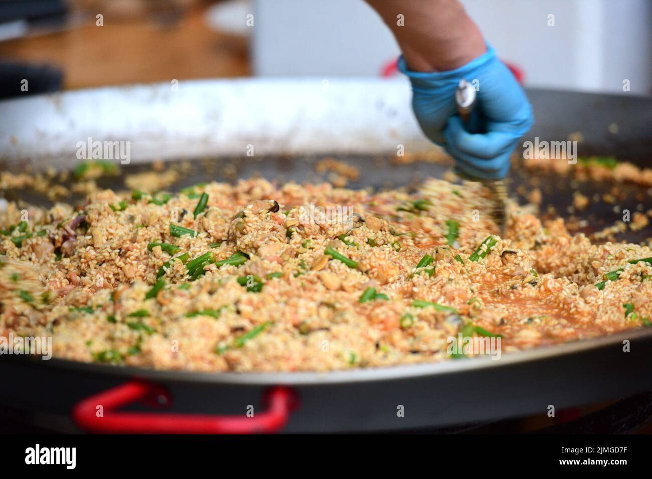 Zubereitung einer Paella in einer großen Pfanne - Preparing a paella in a large pan Stock Photo