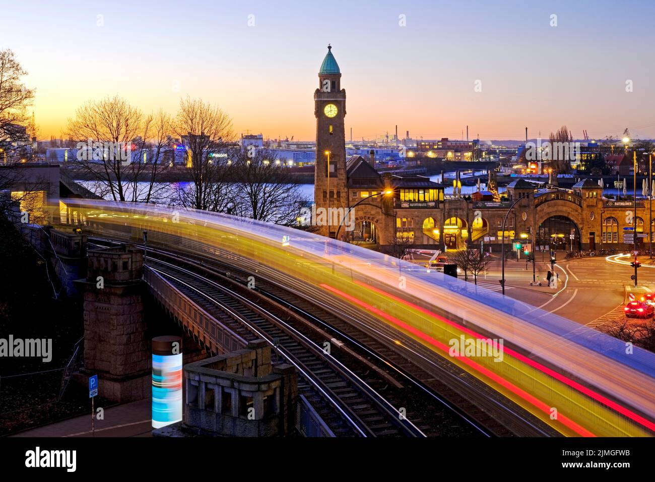 Light trails from the moving elevated train and clock tower at sunrise, Landungsbruecken, Hamburg Stock Photo