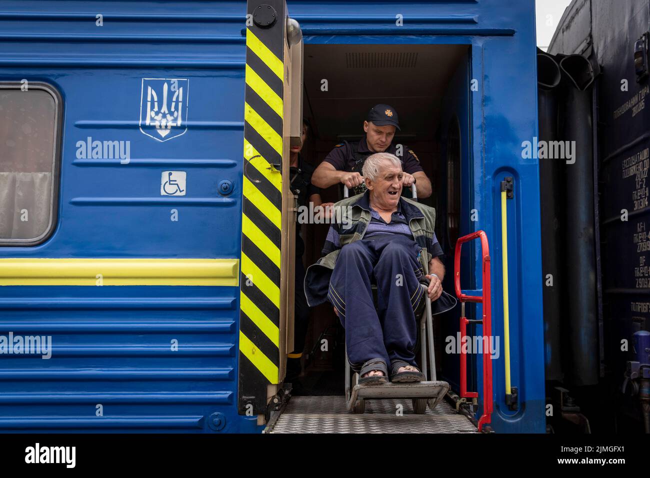 A police officer assists an old man in a wheelchair to board the evacuation train at Pokorvsk Train Station, Donetsk. Amid the intensified fighting in the Eastern part of Ukraine, east Ukraine is now intensifying its civilian evacuation, as millions of Ukrainian families have been evacuating from the closer and closer war, as many of them will be relocated to the western part of the country. According to the United Nations, at least 12 million people have fled their homes since Russia's invasion of Ukraine, while seven million people are displaced inside the country. Stock Photo