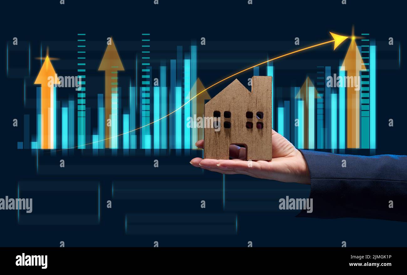 Hand holds a wooden model of a house on a dark background. Real estate