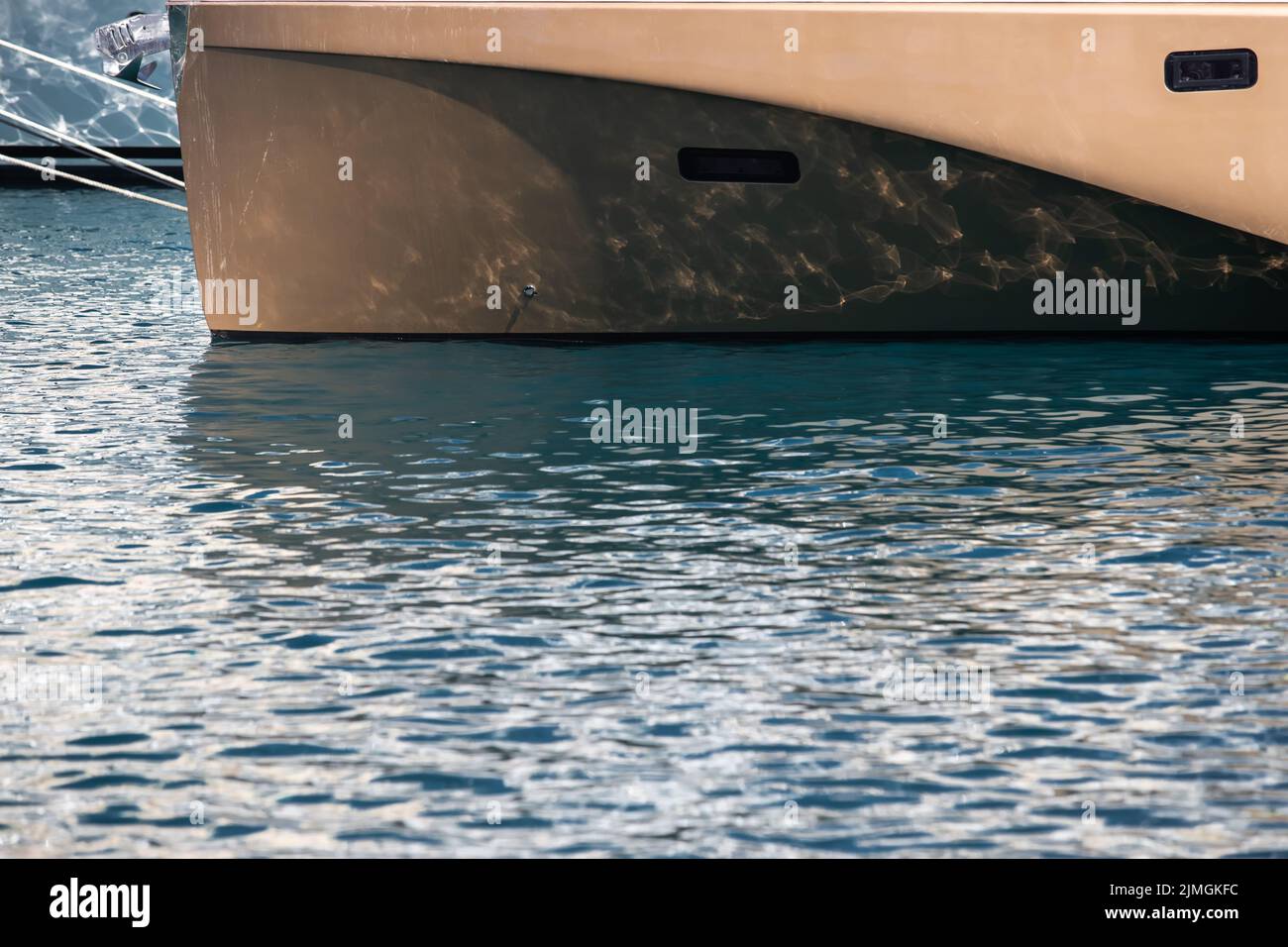 The mesmerizing reflection of the water on the glossy side of a huge yacht anchored, chrome details Stock Photo