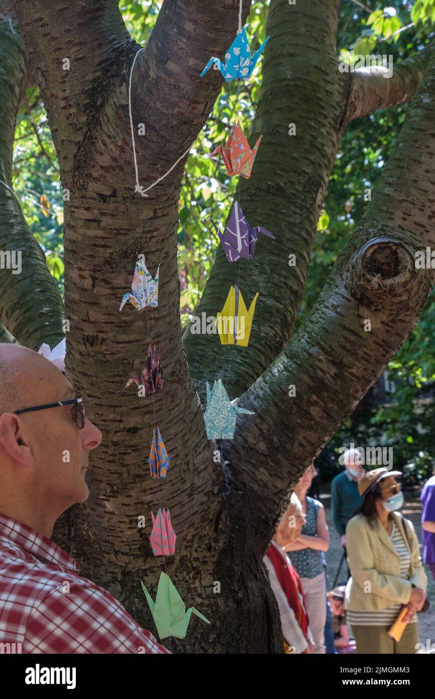 London, UK. 6 Aug 2022. The tree decorated with origami cranes. 77 years after atomic bombs were exploded over Hiroshima and Nagaski, London CND met at the Hiroshima Cherry tree in Tavistock Square to remember the  over 350,000 living in the cities killed immediately or in the next few months. They also remembered survivors still suffering and called on the UK government to end its nuclear weapon programme, end US storing nuclear weapons in the UK and sign the UN treaty prohibiting nuclear weapons. Peter Marshall/Alamy Live News. Stock Photo