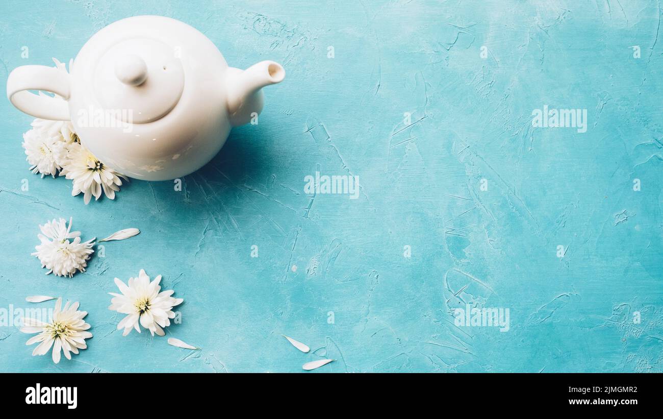 herbal tea teapot daisy flowers blue background Stock Photo
