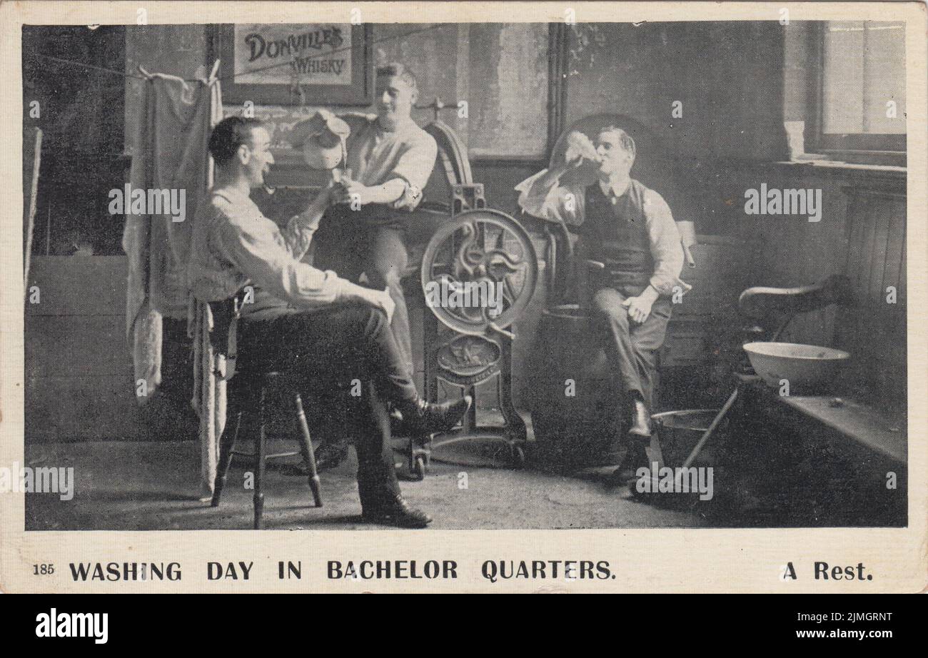 'Washing day in bachelor quarters. A rest': Edwardian comic postcard showing three men attempting the laundry in their bachelor pad. This image shows the men pausing for a drink and a smoke. In the background can be seen a mangle, a shirt on a washing line, a wash tub and dolly, washing coppers, a range and a sign for Dunville's whisky Stock Photo