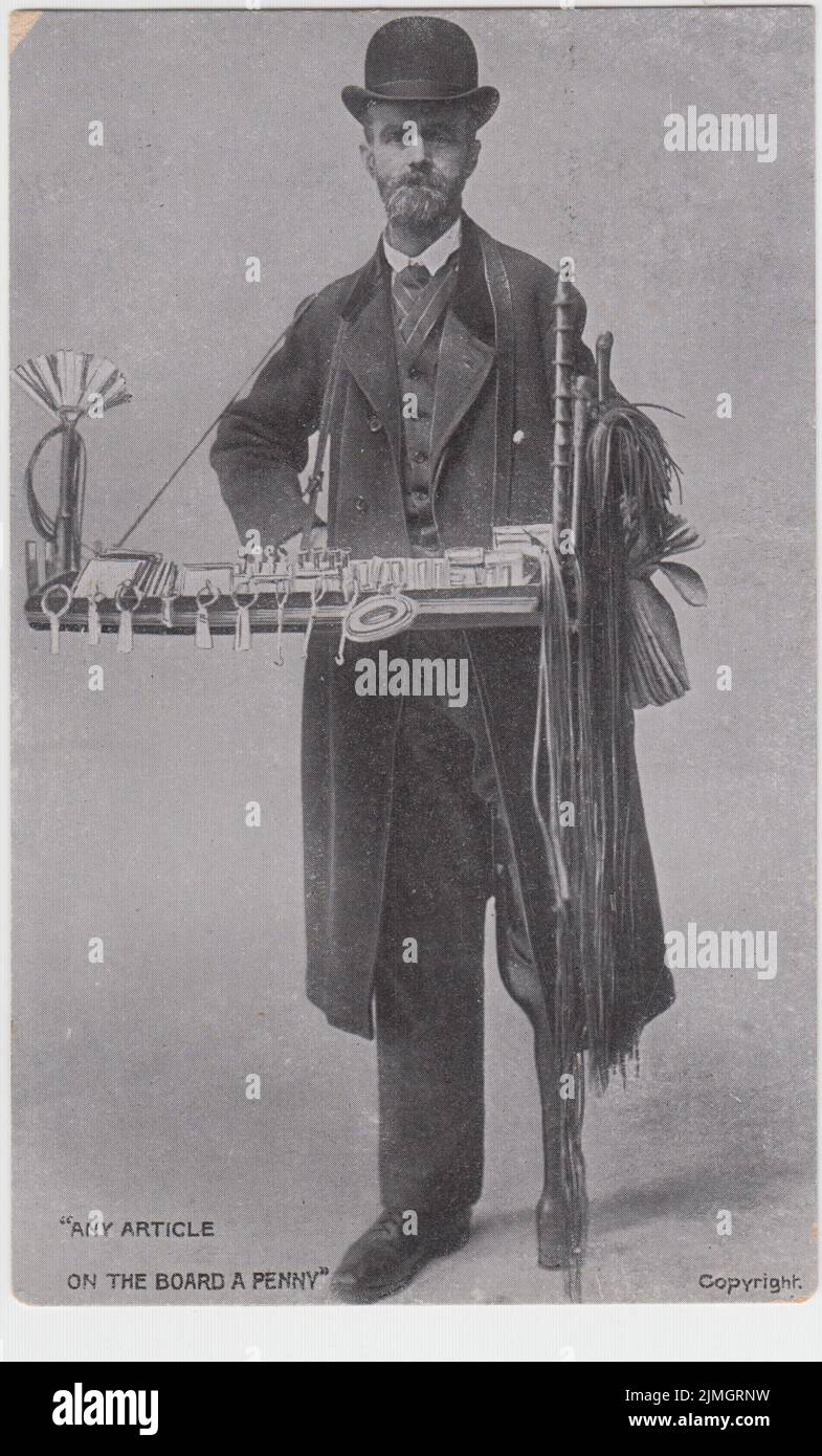 'Any article on the board a penny': Edwardian postcard of a peddler or street seller was a tray of novelty items and keepsakes. The man is smartly dressed, with a bowler hat, and has a wooden leg Stock Photo