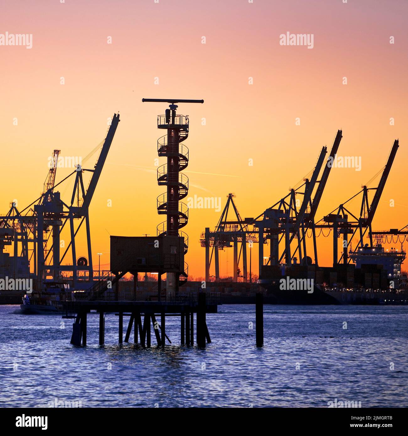 Radar tower and loading cranes at the Burchradkai container terminal at sunset, Hamburg, Germany Stock Photo