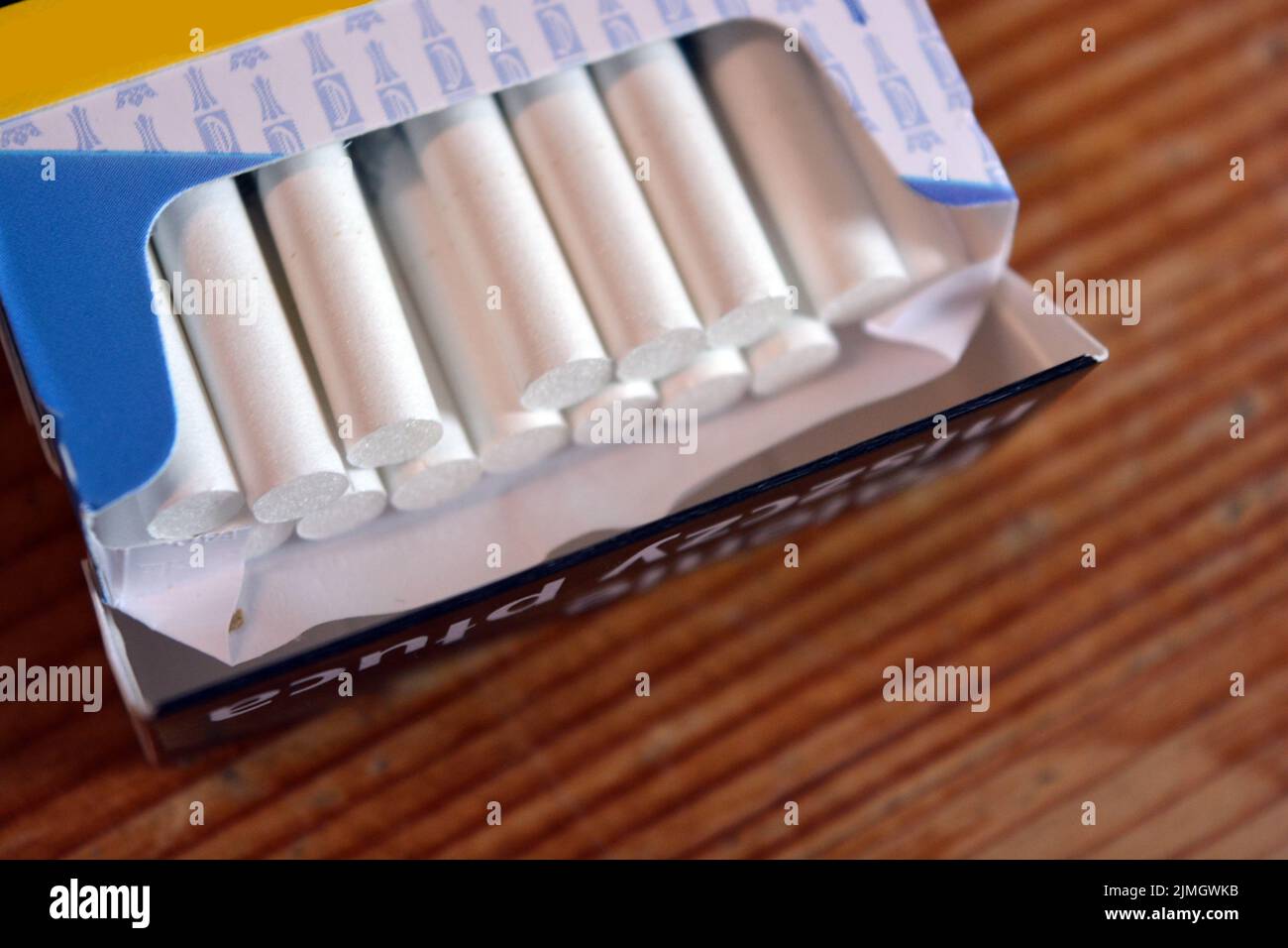A pack of white thin cigarettes lying on a yellow wooden table. Stock Photo