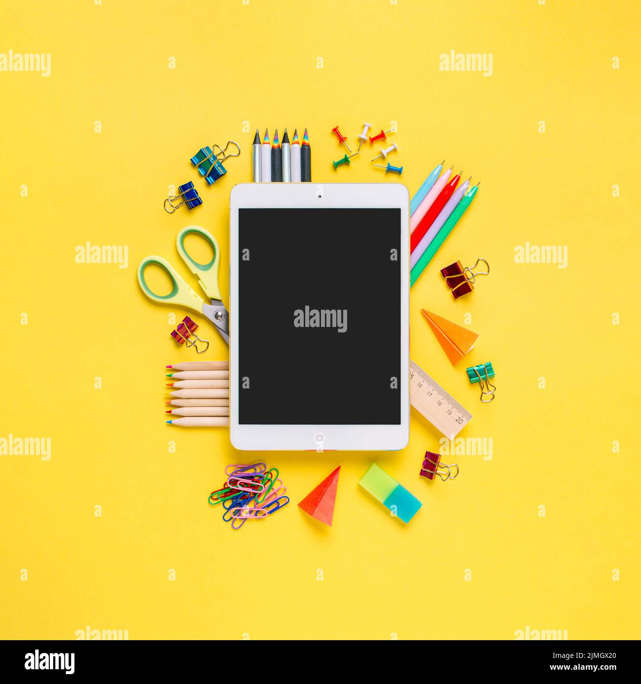 Online study, distantly learning class. Online education, back to school, freelancer work concept. Tablet pc and school supplies, stationery accessories on colored yellow background. Flatlay, top view Stock Photo