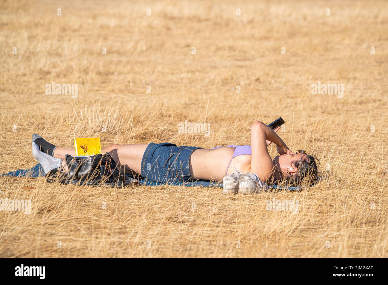 Wimbledon, London, UK. 6 August 2022  A  woman  relaxing in the afternoon sunshine on the parched  grass of Wimbledon Common  as the hot weather and a lack of rainfall continue to grip much of the south of England and the UK, with temperatures expected to reach  above 30celsius  by next week Credit. amer ghazzal/Alamy Live News Stock Photo