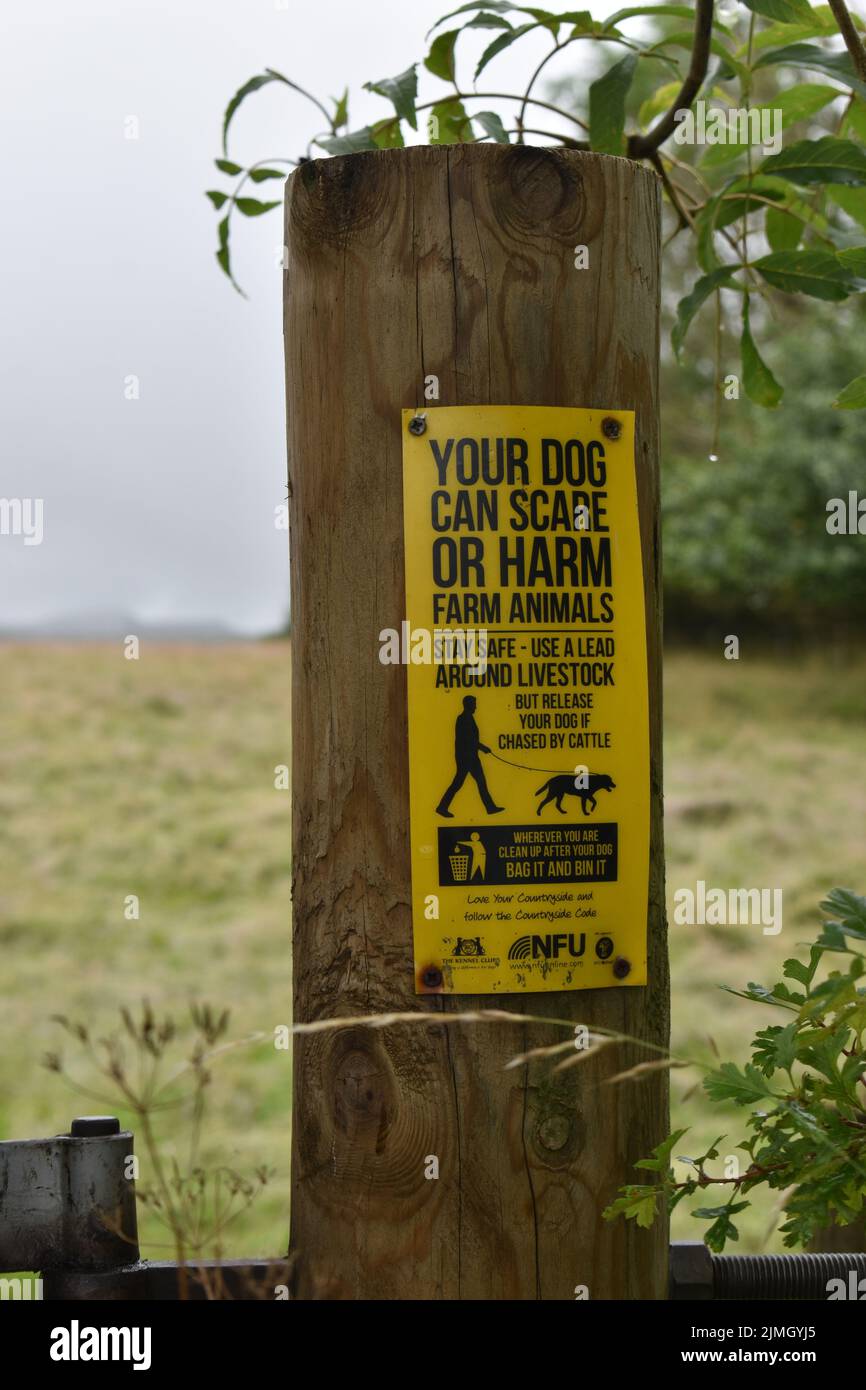 Sign on a post: 'Your dog can scare or harm farm animals'. Stock Photo