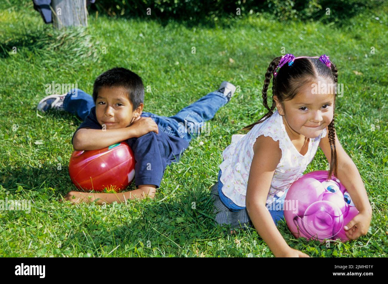 Native American sister and brother play with orange slices and make smiles. brother and sister play with colorful balls on grass, Fort Hall Idaho. Stock Photo