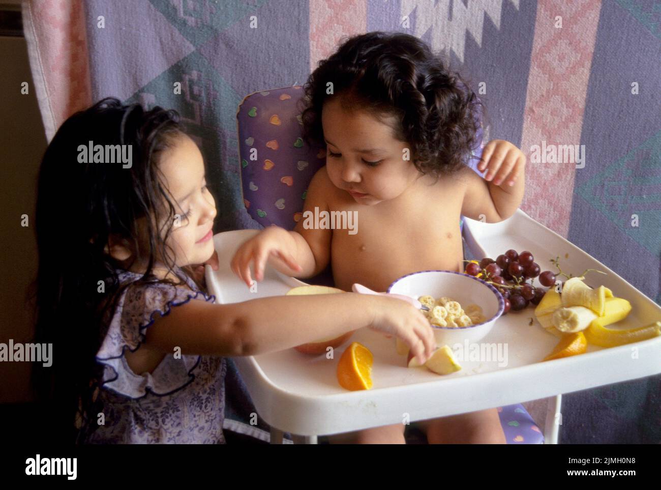 Native American family of two sisters share healthy nutritional food together of fruit and cereal Stock Photo