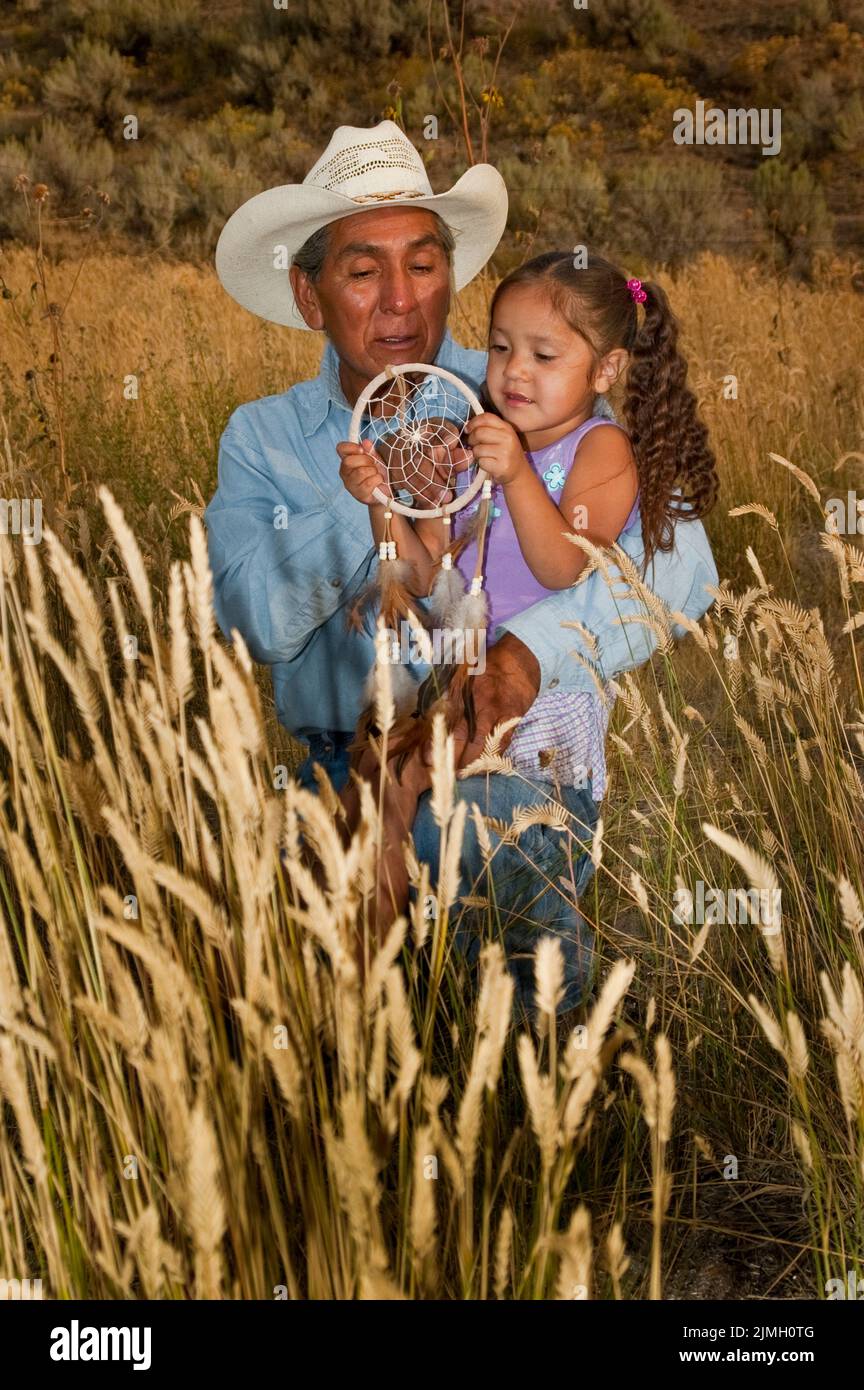 Grandfather hands down tradition nad tells a story to his granddaughter about the dreamcather Stock Photo