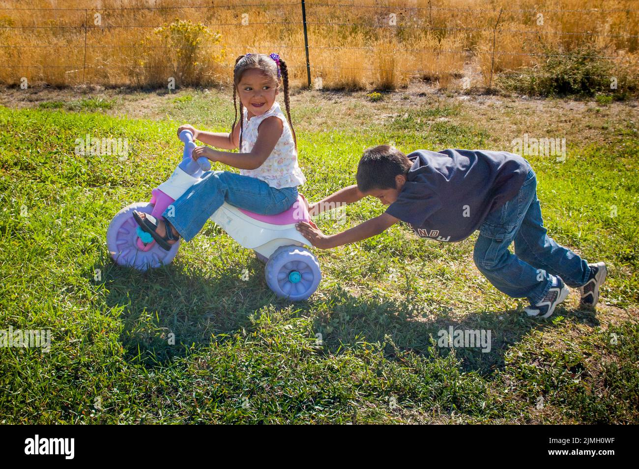 Older brother teaches his little sister how to ride her bike, Fort Hall, Idaho Stock Photo