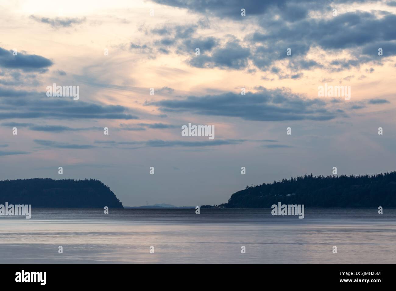Dramatic Sun setting behind storm clouds over the Puget Sound Stock Photo