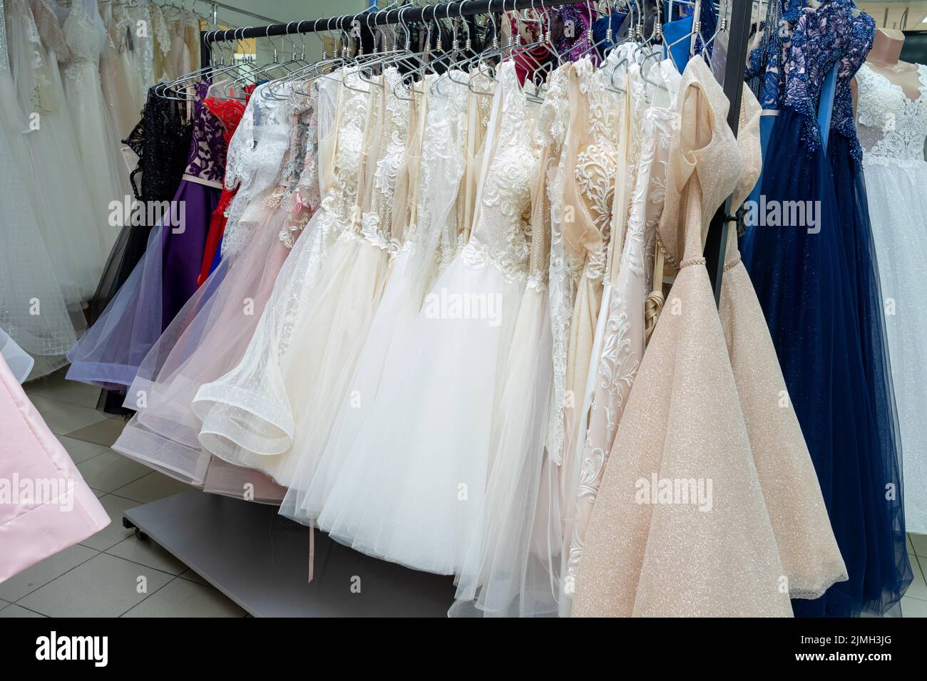 Many different evening dresses and bridal dresses on a hanger in the store Stock Photo