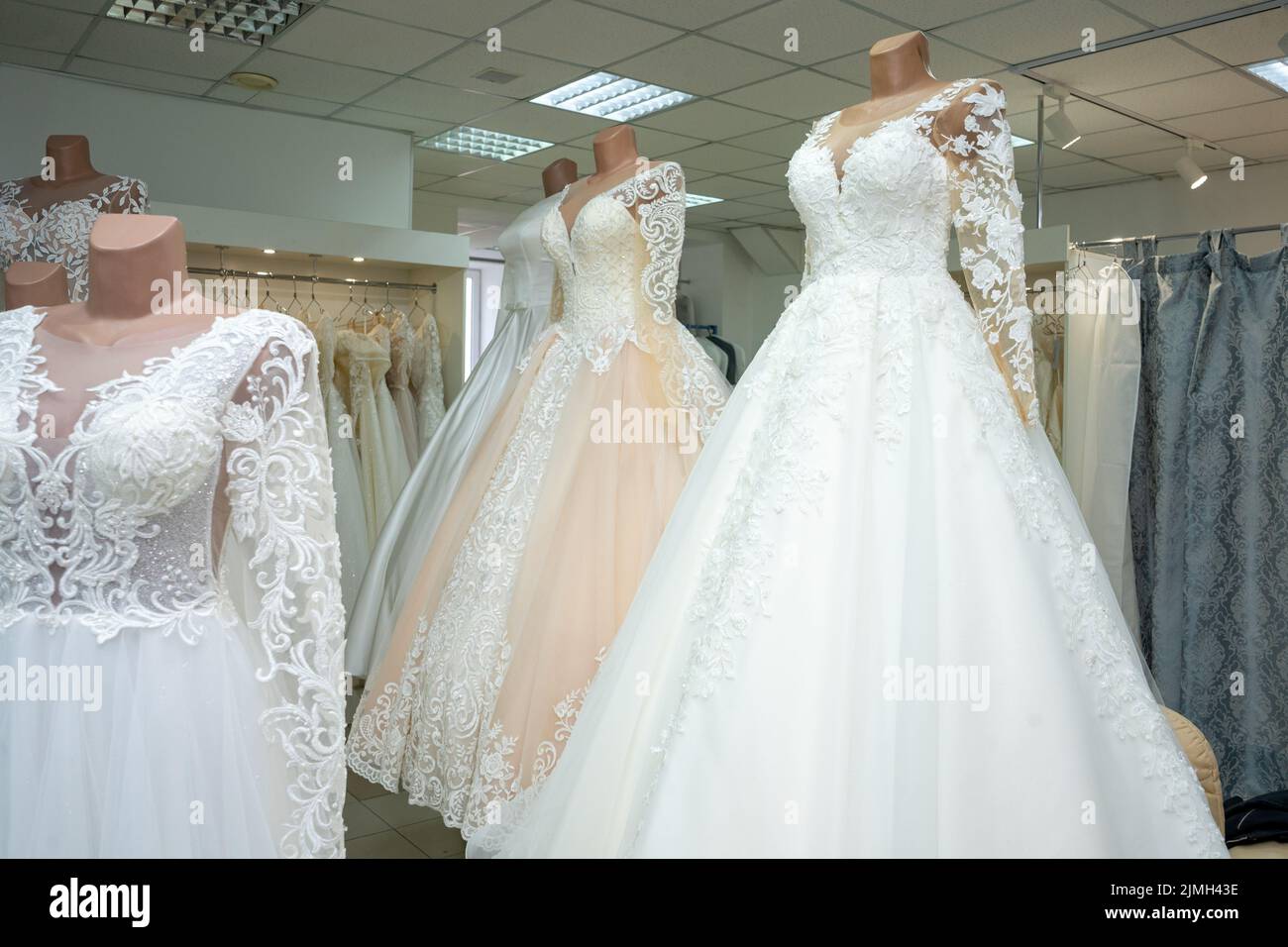 Beautiful wedding dresses in a bridal boutique on mannequins Stock Photo